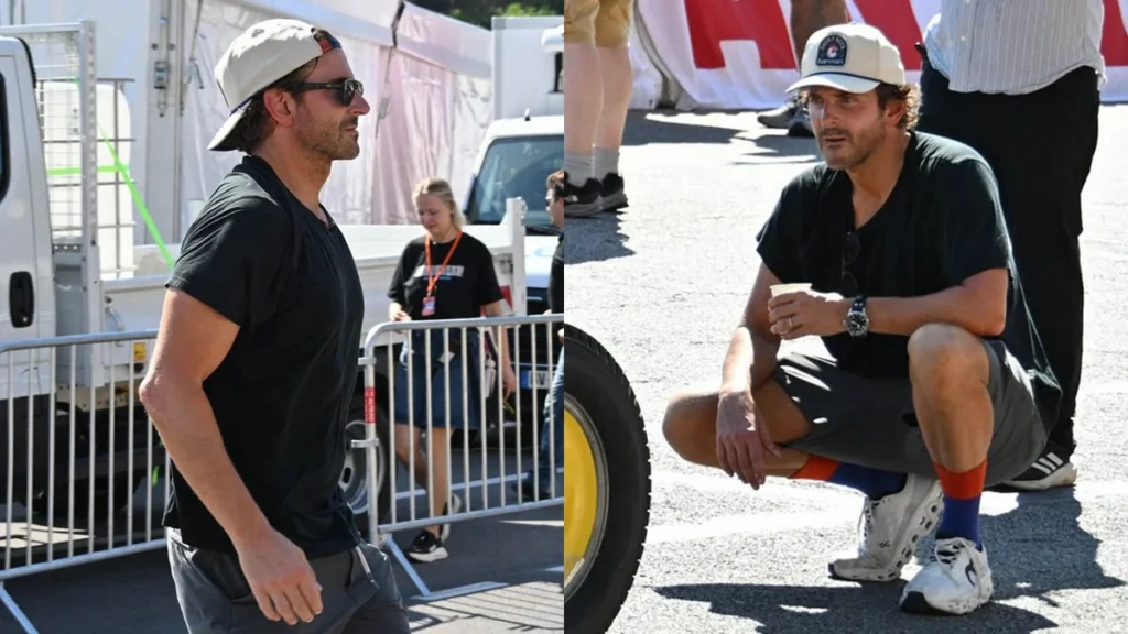 Bradley Cooper wearing sunglasses and a baseball cap while filming in Monaco near vintage racing cars.