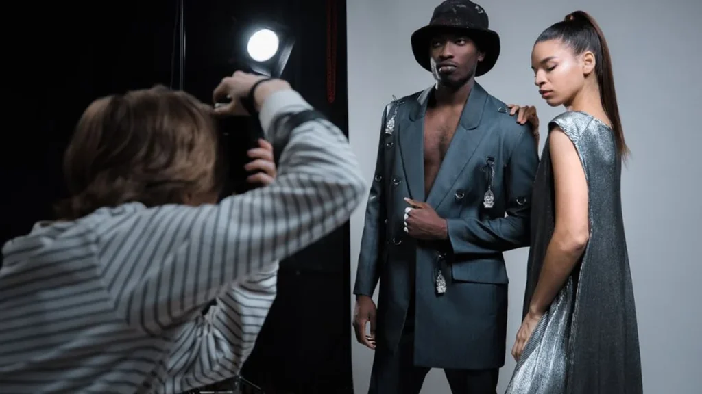 A stylish male fashion architect posing among luxury designer clothing and vintage accessories.