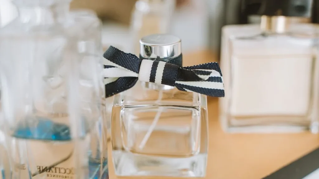 A Guerlain perfume bottle surrounded by blue iris flowers and flowing blue silk fabric.