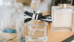 A Guerlain perfume bottle surrounded by blue iris flowers and flowing blue silk fabric.
