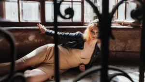 Woman wearing an ivory ruffled lace dress with a black leather jacket for a modern Victorian look.