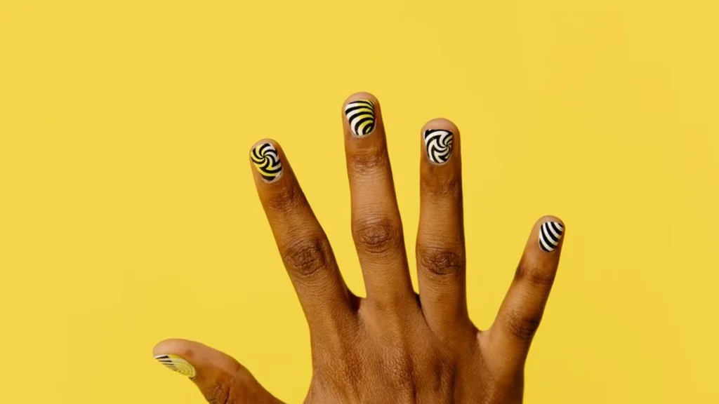 Close up of mismatched abstract nail art featuring animal prints and earthy fall colors on chrome.