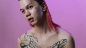 A close-up portrait of Nettspend with magenta hair and a sequined shirt.