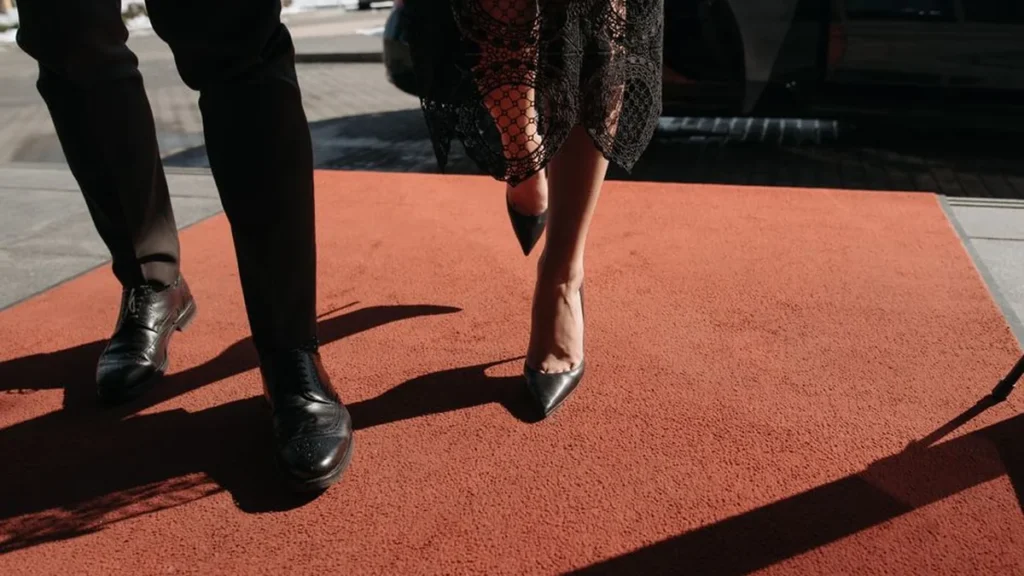 An empty elegant red carpet at a formal gala event with velvet ropes and flowers.