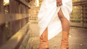 Close up of weathered leather boots and historical linen clothing on a dark surface.