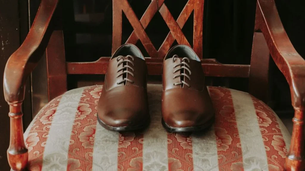A collection of espresso, merlot, and two-tone shoes resting on a reflective chrome surface.
