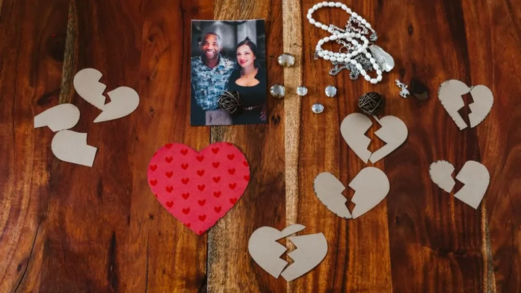 A cracked glass picture frame with a faded family photo resting on a dark table.