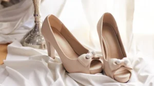 High-heeled shoes and silk fabric resting on a reflective chrome surface.
